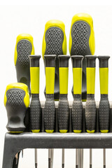 Set of yellow and black screwdrivers arranged in a holder on a white background