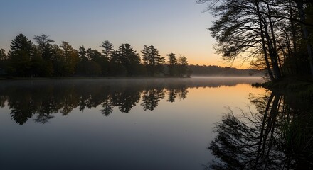 Fototapeta premium Calm lake at sunrise with golden light reflecting trees and serene nature creating peaceful scenery