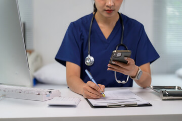 Healthcare professional multitasking with phone, writing medical records
