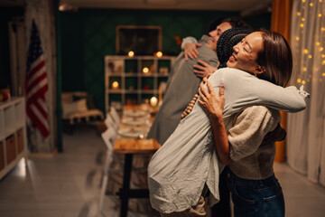 Friends embracing at thanksgiving dinner party celebrating with usa flag in background