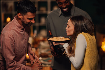 Woman smelling freshly baked pie at thanksgiving dinner with friends