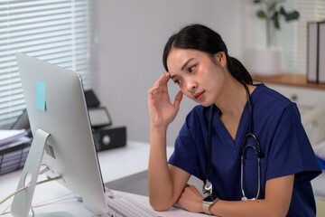 Asian nurse feeling tired and stressed at office desk after long shift