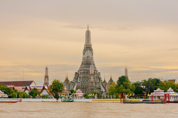 Naklejka premium Wat Arun, the Temple of Dawn in Bangkok, renowned for its towering prang adorned with colorful porcelain, shimmering beautifully at sunrise and sunset.