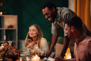 Chef serving thanksgiving turkey to grateful friends at dinner table