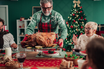 Grandfather bringing christmas turkey to family dinner table