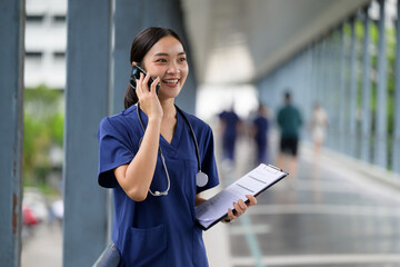 Asian female nurse using phone call in hospital corridor
