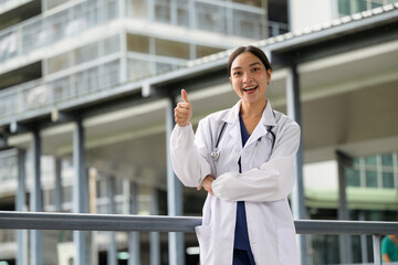 Female doctor giving thumbs up standing outdoors