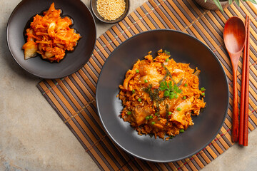 Kimchi fried rice with pork belly topped with sesame seed and Crispy Seaweed in black plate.Korean food.Top view.