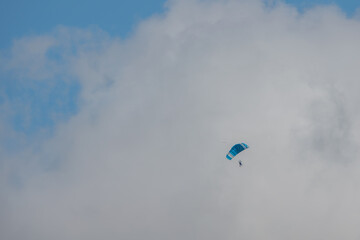 parachuter descending with blue sky and white clouds in the background in Salisbury Wiltshire