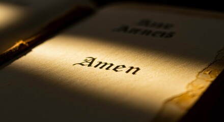 Close-up of the word 'Amen' in a book, illuminated by soft light creating a sense of reverence and