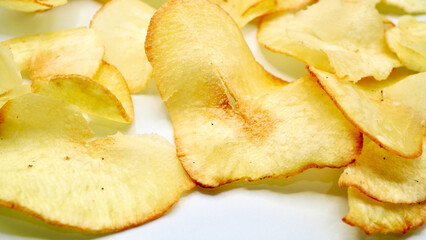 Pile of golden crispy cassava slices photographed on a white table. Ideal for advertising, menus, or editorial food content
