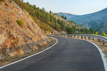 Scenic route with sharp curves where the road seems to merge with the slopes covered in moss and multi-colored lichens