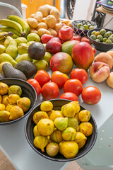 Fresh market composition with seasonal figs, water pears, Hass avocados, Kenebec potatoes, and nectarines on a sky blue table