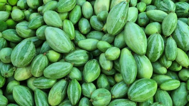 A pile of parwal, also known as pointed gourds, is displayed for sale at a shop, showcasing fresh vegetable stock.