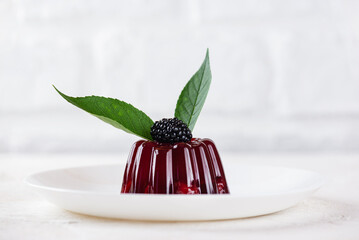 Jelly dessert with blackberry on white plate. Vegan, sugar and lactose free.