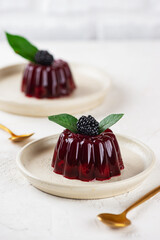 Jelly with fresh cherry and blackberry in a plate on light table. Healthy food, vegan, sugar, gelatin and lactose free. Vertical orientation.