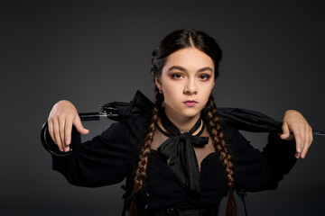 Gothic girl in braids channels spooky vibes for Halloween in a striking dress