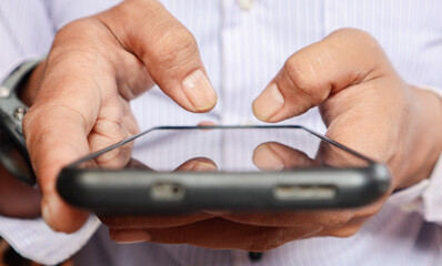 Close up view of man's hands typing a message on a smart phone. 