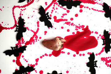 Raw heart with red paint splatters surrounded by black bat silhouettes, surreal horror still life...