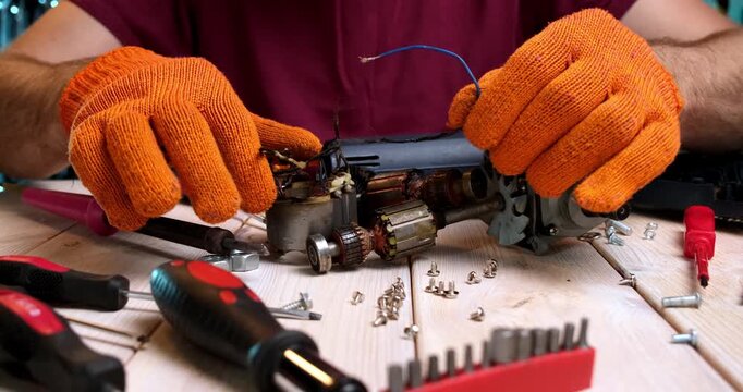 Repair of power tools. A master in a repair shop repairs a power tool