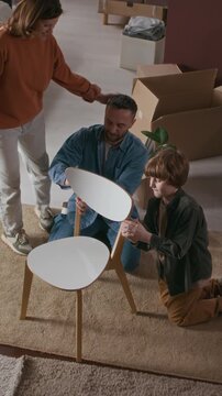Vertical shot of happy woman thanking her husband and little son for assembling cheir together