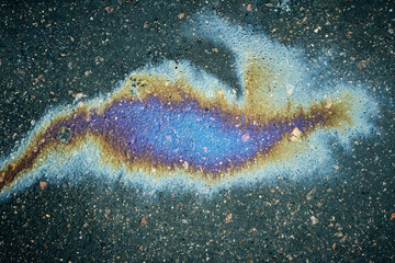 Oil slick creating abstract colorful pattern on wet dark asphalt