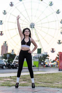 Urban fitness female doing jumping jacks in city park, Asuncion, Paraguay