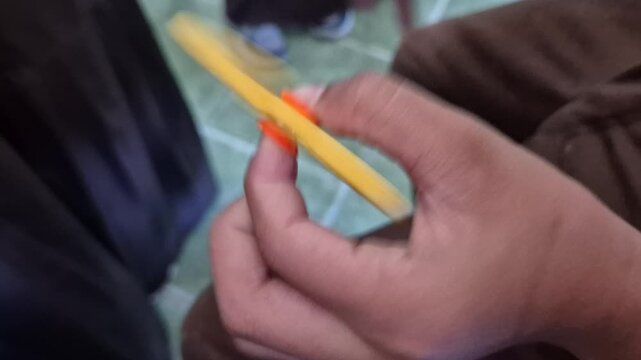 Close up of elementary school student play spinning yellow fidget spinner on hand in classroom. Slow motion 4k video