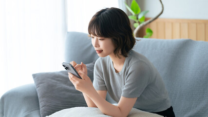 ソファに座ってスマートフォンを使う女性