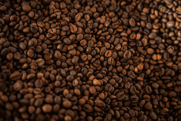 Close-up pile  of roasted coffee beans with rich brown tones and textured surface, emphasizing freshness, quality, and aromatic appeal.