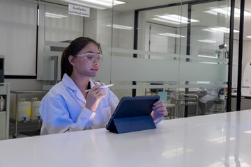 Scientist conducts research in a modern laboratory using a tablet and wearing safety goggles during the daytime
