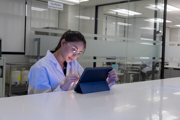 Scientist working diligently on tablet in modern laboratory setting during evening hours