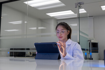 Scientist working in a modern laboratory, using a tablet to analyze data and conduct research during the day