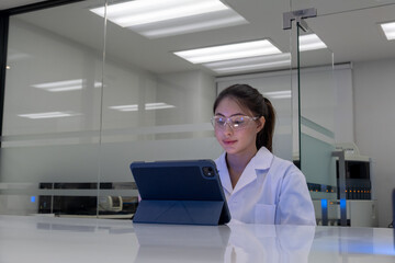 Young scientist working in a modern laboratory using a tablet for research during the day