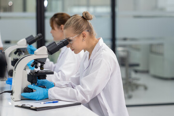 Young scientist examines samples under a microscope in a modern laboratory setting during the daytime