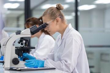 Scientist examines samples at laboratory using microscope during research work in modern facility