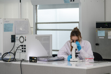 Scientist studying samples using a microscope in a modern laboratory during the daytime