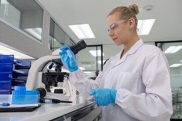 Scientist examines sample under microscope in modern laboratory setting during daytime