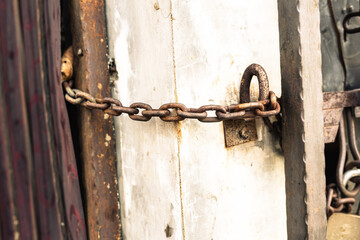 Rusty Chain Securing Metal Gate on Concrete Wall