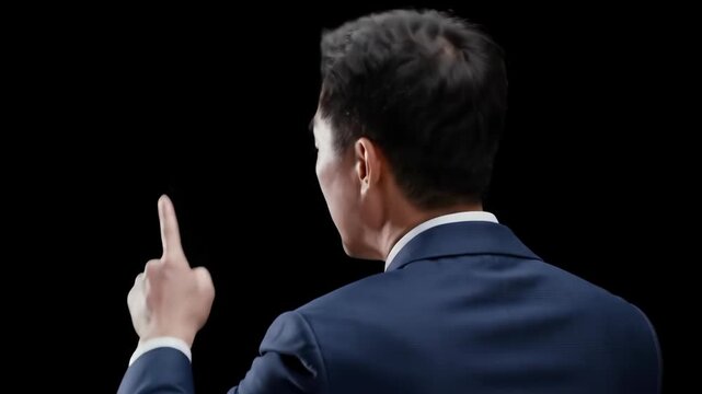 A man in a suit pointing his finger up against a black background.