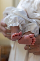 Close-up of newborn baby feet in white christening clothes. Tender moment of baptism, symbol of purity, new life, innocence, spirituality, tradition and family values in Ukrainian Greek Catholic Churc