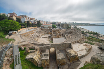 Tarragona Roman amphitheatre ruins above the Mediterranean, ancient arena with beachside city view and soft morning light; ideal for travel and heritage campaigns.