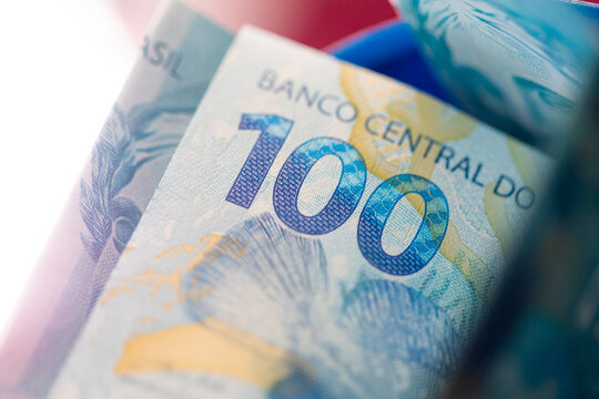 Dinheiro, Brasil, Real. Notas de 100 reais dentro de um cofrinho de pl&aacute;stico. Economia, poupan&ccedil;a, investimento,  fgts, previd&ecirc;ncia, aposentadoria.