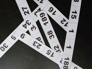 Abstract arrangement of measuring tape segments with prominent numerical markings and a dark