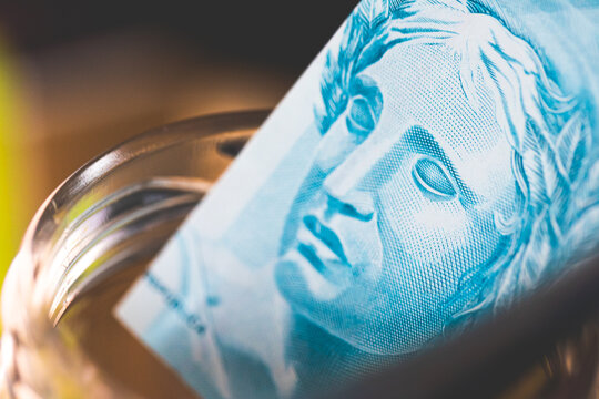 Dinheiro, Real, Brasil, Macro de uma nota de 100 reais em um pote de vidro. Investimento, Selic, Ipca, Poupan&ccedil;a, aposentadoria, seguro social, fgts.