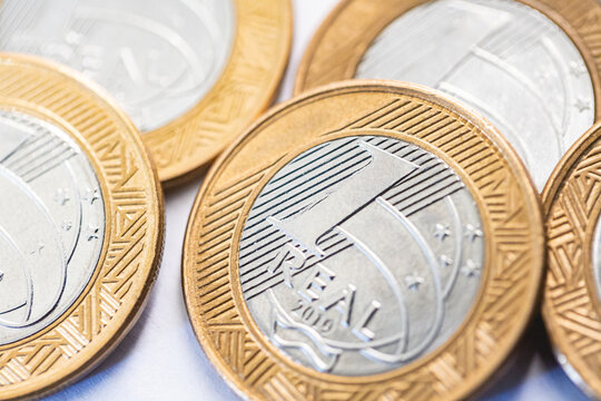 Dinheiro, Brasil, Real, 1 Real. Moedas de 1 Real em fotografia macro em superf&iacute;cie branca. Economia brasileira, selic, banco central,  ipca, fgts, impostos.