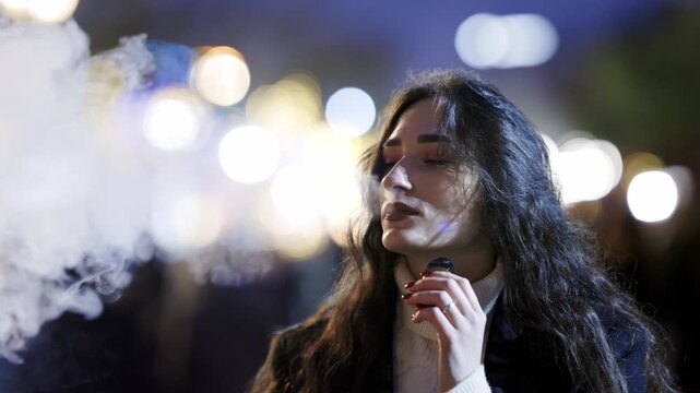 Young woman vaping electronic cigarette at night