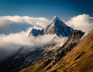 Majestic Mountaintop Surrounded by Clouds Under a Clear Blue Sky