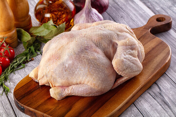 Raw whole chicken over board