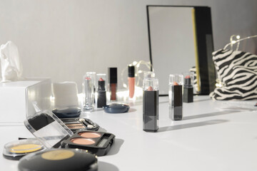 Makeup station at the beauty store. Cosmetics for testing. Lipsticks, blushes, poweder foundations, mirror on white makeup counter
